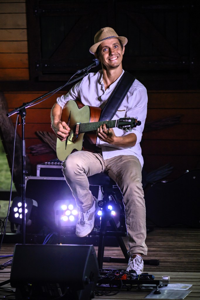 Un guitariste est sur scène et sourit à la caméra