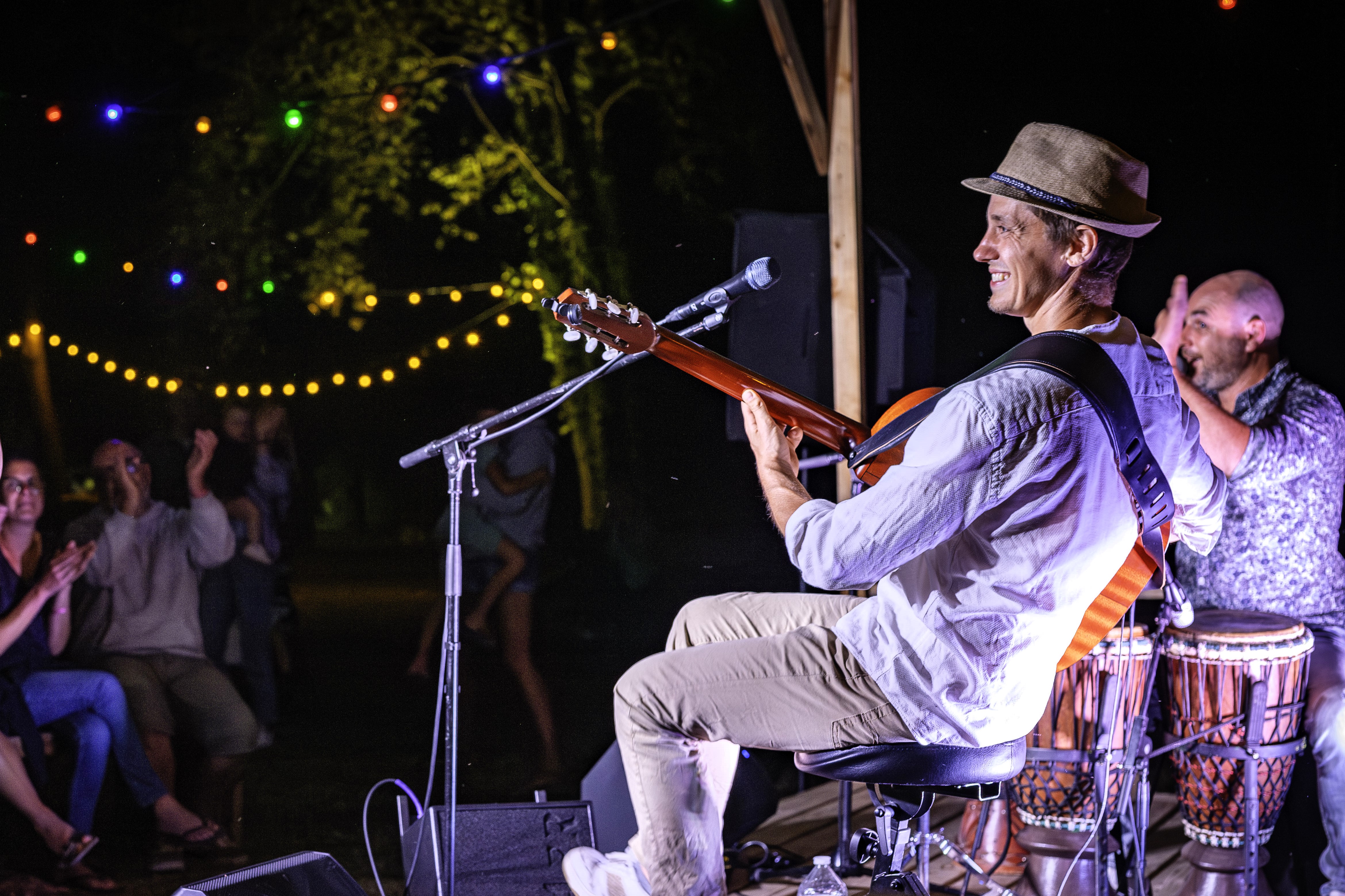 un chanteur guitariste au premier plan et un percussionniste tapant dans ses mains au second plan